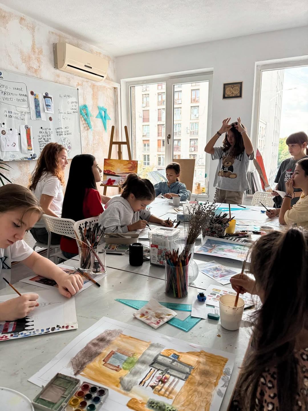 Grup de copii 10–14 ani lucrând împreună la o natură statică