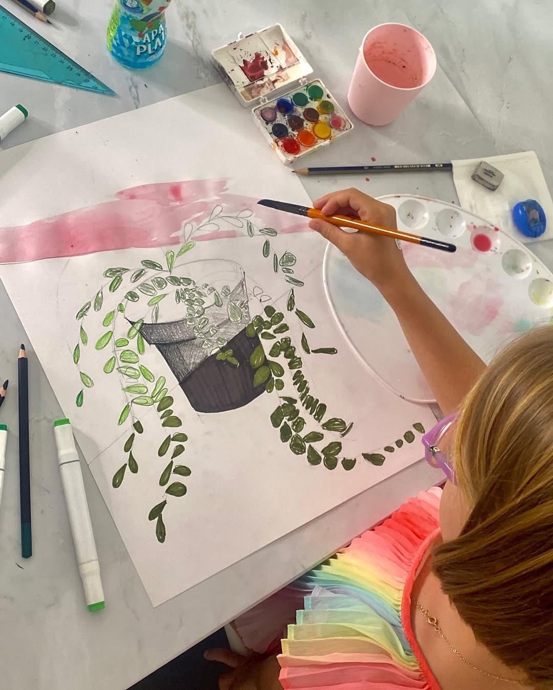 Copil zâmbind în timp ce pictează la un șevalet